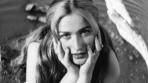 Black and white photo of Imogen resting her head on her hands and lying on the floor