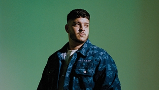 Photo of Bou wearing a blue shirt in front of a green background