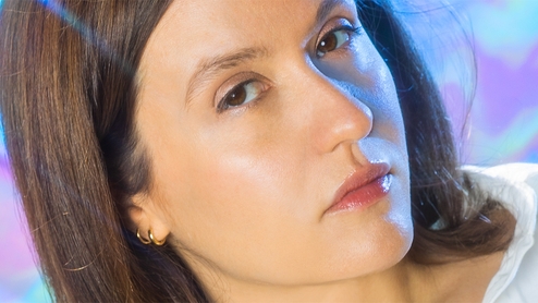 Jessy Lanza seen up close in front of a purple and blue background