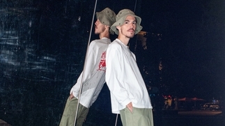 Photo of Simo Cell leaning against a wall wearing a beige bucket hat and cargo trousers