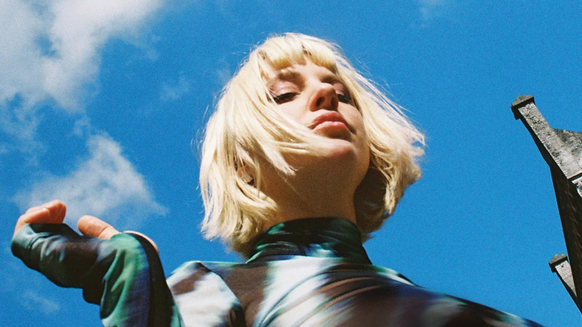 Photo of Alberta Balsam wearing a silver shirt and posing against a blue sky