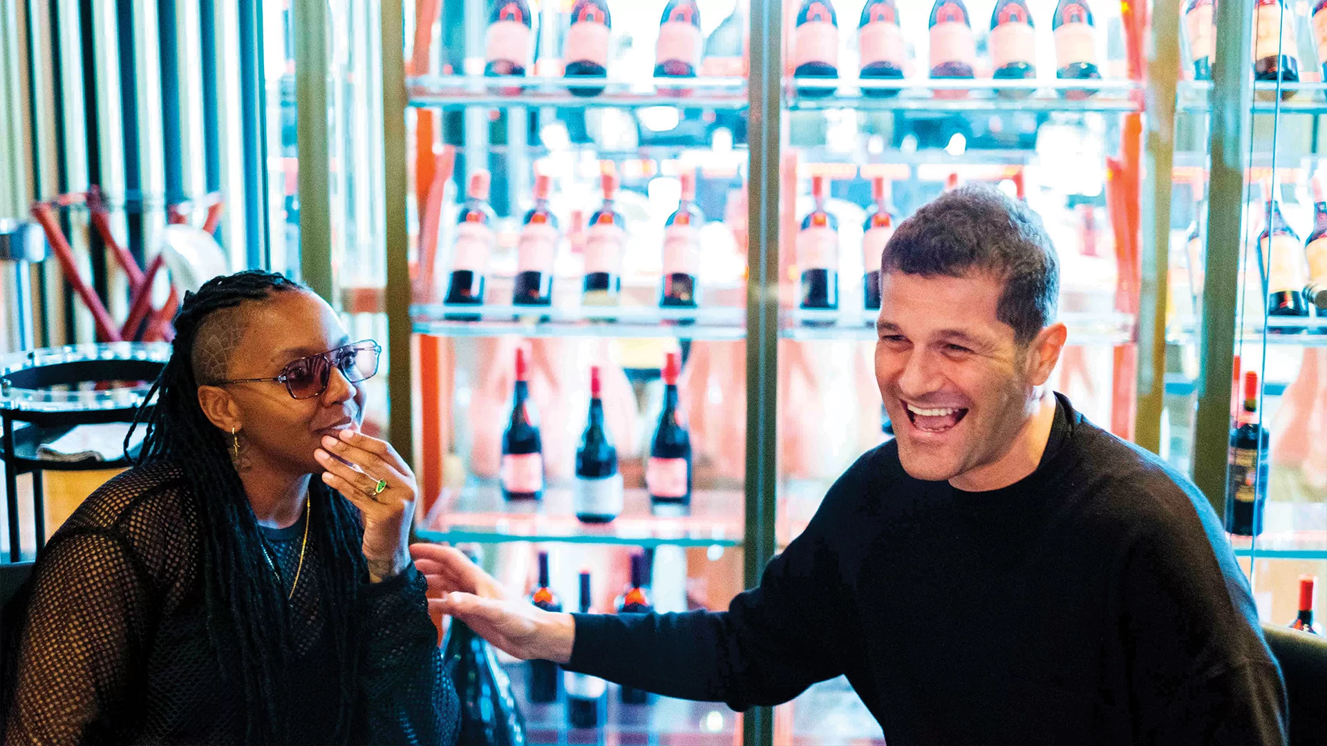 Photo of SYREETA and Andrea Olivia laughing in a colourful wine bar